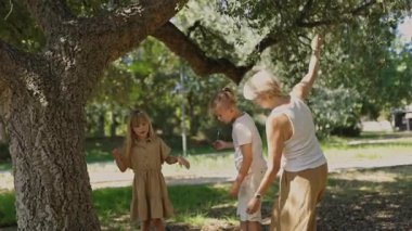 Anne ve çocuklar parkta birlikte vakit geçiriyorlar, eğlenceli etkileşimlere giriyorlar.