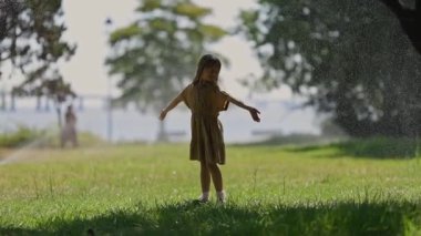 Tasasız çocuk parkta su fıskiyesinin keyfini çıkarıyor.