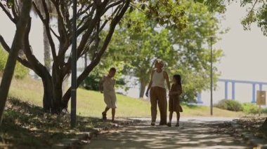 Büyükannem, güneşli bir parkta yürürken torunlarıyla el ele tutuşmaktan zevk alır.