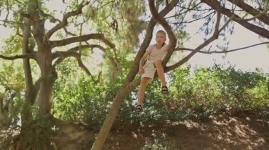 Mutlu çocuk ormandaki bir ağaç dalında oturmaktan hoşlanıyor.