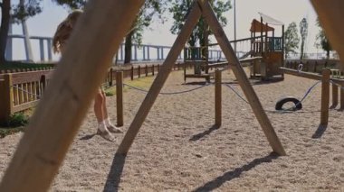 Çocuk parkında salıncaktan hoşlanan genç bir kız, Vasco da Gama köprüsü arka planda görünür.