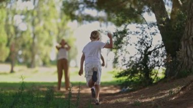 Güneşli bir parkta koşan ve oynayan mutlu çocuklar.