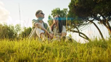 Parkta çimlerde oturan şık çift yaz gününün tadını çıkarıyor.