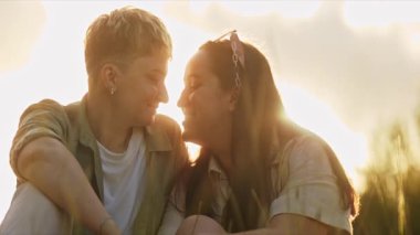 Genç lezbiyen bir çiftin güneşli bir alanda sevgisini paylaştığı romantik anlar.