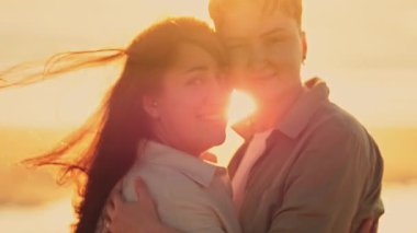 Romantik lezbiyen çift, altın bir günbatımında kumsalda hassas bir anın tadını çıkarıyor.