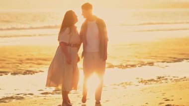 Romantik lezbiyen çift gün batımında sahilde yürüyüş yapıyor, özel anlarını paylaşıyorlar.