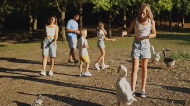 Aile güneşli bir günü parkta geçirir, ördekleri besler ve doğanın tadını çıkarır, birlikte neşeli açık hava anıları yaratırlar.