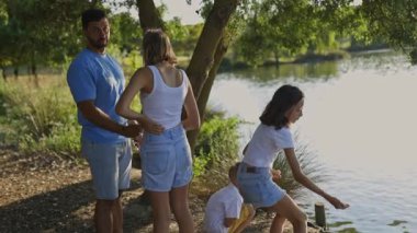 Mutlu bir aile, güneşli bir öğleden sonra gölün kenarında kuğuları besliyor.