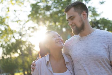 Parkta romantik bir anın tadını çıkaran ırklar arası bir çift birbirlerine sevgi ve sevgiyle sarılıyorlar.