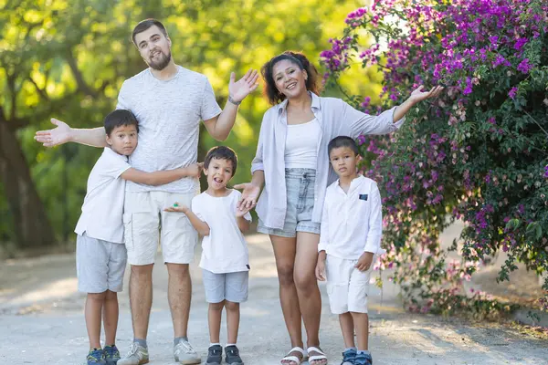 Çok ırklı bir aile parkta gülümsüyor ve birlikte poz veriyor.