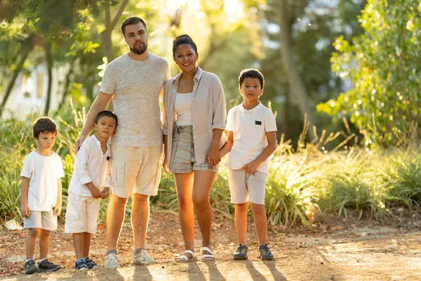 Mutlu bir aile parkta güneşli bir günün tadını çıkarıyor, birlikte uzun süreli anılar yaratıyorlar.