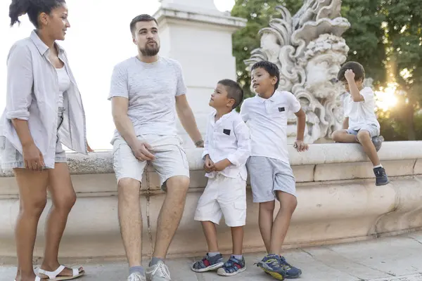 Mutlu aile sohbetleri ve yaz tatilleri şehir parkındaki bir çeşmenin yanında oturmak.
