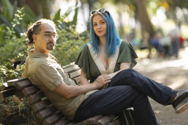 Parktaki bankta oturan genç çift, evcil fareleriyle güneşli bir günün tadını çıkarıyorlar.