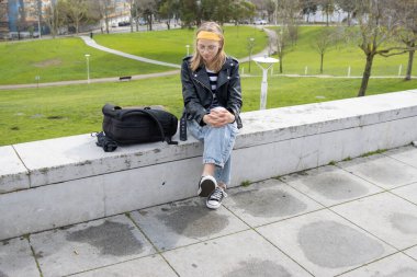 Parkta beton bir bankta oturan bir kadın, huzurlu bir anın tadını çıkarıyor.