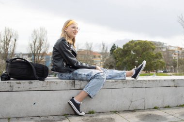 Okuldan sonra parkta gülümseyen ve dinlenen genç bir kız öğrenci.