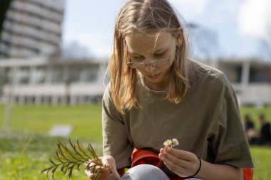 Biyoloji öğrencisi kampüste çiçek ve bitki topluyor.