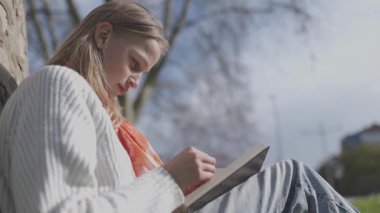 Huzurlu bir parkta kitap okuyan bir kız.