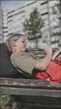 Genç öğrenci yalan söylüyor ve bankta oturuyor. Not defterine yazıyor.