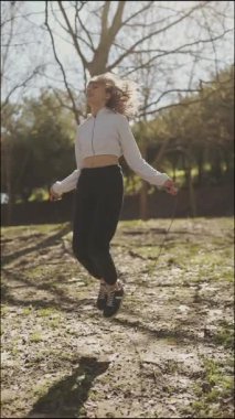 Fitness modeli bir parkta atlama egzersizleri yapar