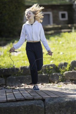 Gençler parkta ip atlarken eğleniyor ve egzersiz yapıyor.