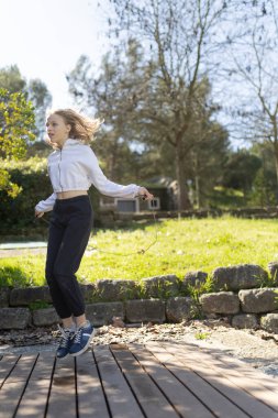 Sağlıklı bir yaşam tarzının tadını çıkaran bir genç, parkta ip atlıyor.