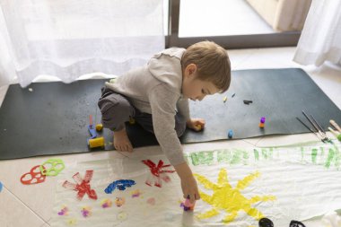 Anaokulunun rengarenk mizaç renkleri ve şablonları ile yerde resim yaparken eğlenmesi yaratıcılık ve hayal gücünü geliştiriyor.