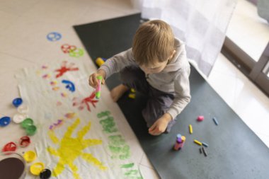 Anaokulu öğrencisinin yeri boyamakla eğlenmesi, yaratıcılığı ve hayal gücünü geliştirmesi.