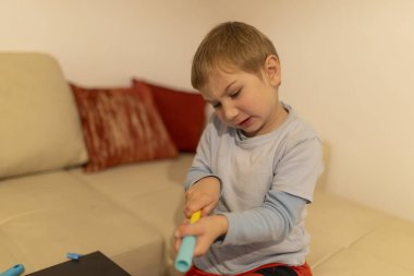 Renkli plastik inşaat oyuncaklarını birleştiren, iyi motor becerileri ve yaratıcılığı geliştiren konsantre genç çocuk.