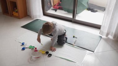 Yaratıcı çocuk yerde parmak boyamaktan zevk alıyor, renkleri keşfediyor ve sanatsal beceriler geliştiriyor.