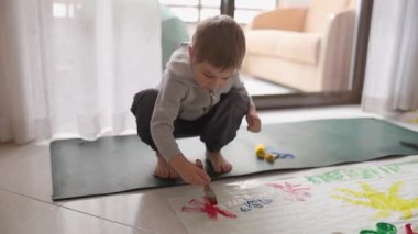 Çocuk yaratıcı oyun zamanını seviyor, yere renkli resimler çiziyor.