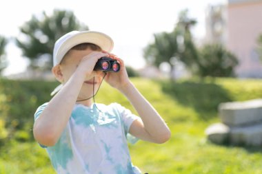 Parkta dürbün kullanan küçük bir çocuk doğa keşfi yapmaktan ve doğayı keşfetmekten zevk alıyor.