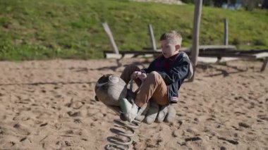 Çocuk oyun parkında el şeklinde bir yay binicisinin üstünde zıplayarak eğleniyor.