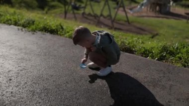 Meraklı çocuk parkta büyüteçle keşif yapıyor.