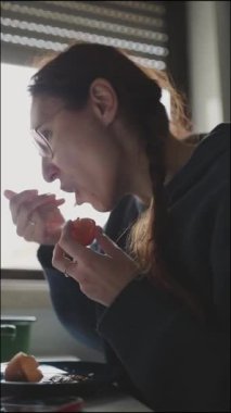 Kızıl saçlı kadın kahvaltıda meyve soyup yiyor.