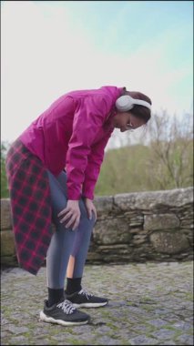 Parkta koştuktan sonra bacaklarını açmak için mola veren aktif bir kadın.