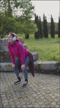 Aktif kadın dışarıda egzersiz yapmayı, çömelmeyi ve sakin bir park ortamında esnemeyi seviyor.