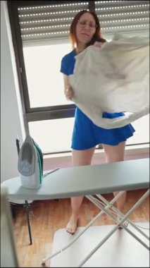 Mutlu ev kadını yeni ütülenmiş gömlekle dans ediyor.