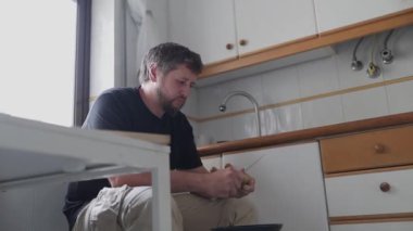 Ev mutfağında bıçakla mango soyan konsantre bir adam.