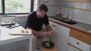 Evcil bir mutfakta patates soyan adam.