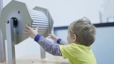 Etkileşimli bir bilim müzesinde optik illüzyon sergisini keşfeden genç bir çocuk.