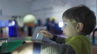 Genç bir çocuk interaktif bir bilim müzesinde ışık ve renk filtresiyle oynuyor.