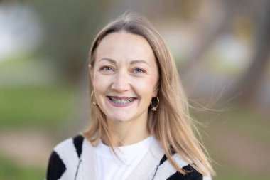 Dişlerinde diş telleri olan gülümseyen bir kadın.