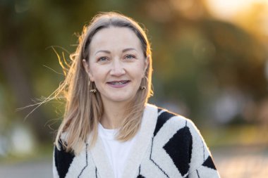 Altın saat boyunca dişlerinde diş telleriyle güvenle gülümseyen kadın, mutluluğu ifade ediyor.