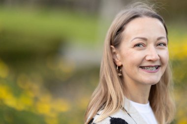 Yetişkin bir kadın, doğal ışıkta diş teli takarken mutlu olur.