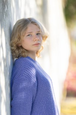 Mor kazak giyen genç bir kadın düşünceli bir ifadeyle başka tarafa bakıyor.