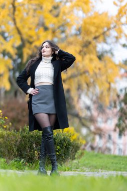 Şık bir sonbahar elbisesi içinde, parka bakan genç bir kadın.