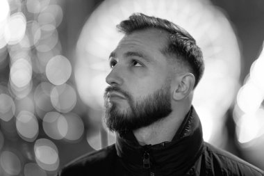 Sakallı adam bulanık şehir ışıkları ve parlayan bokeh 'in arka planına bakıyor.