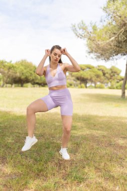 Parkta egzersiz yapan genç bir kadın spor malzemeleriyle dinamik bir egzersiz yapıyor.