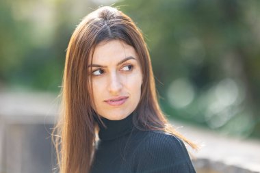 Odaklanmış bir ifadeyle doğal ışıkta arkasını kollayan genç bir kadın.