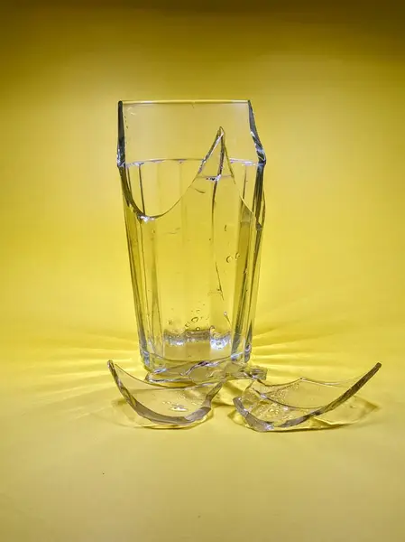 Shards of a broken glass on a yellow background